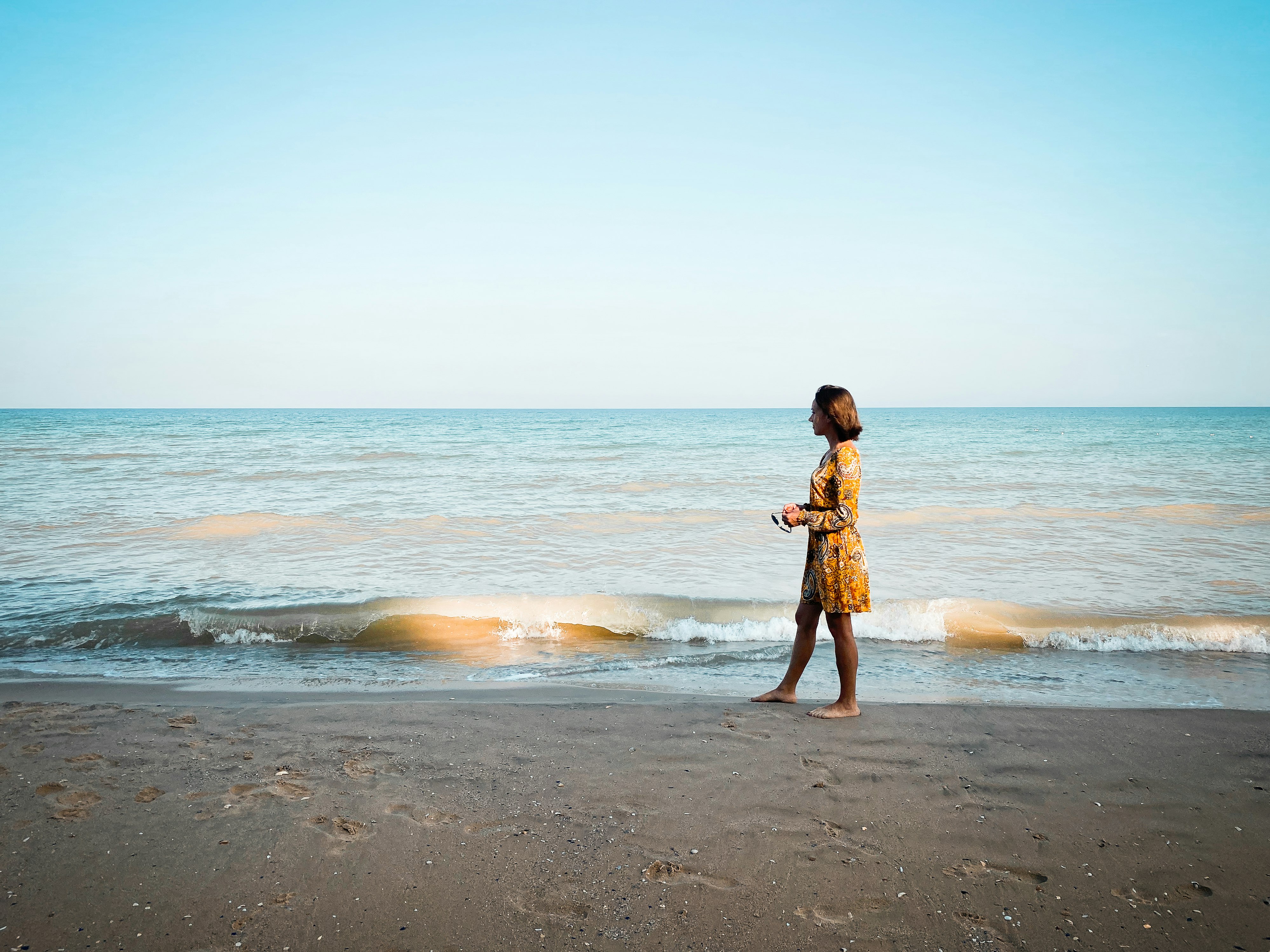 girl in brown dress standing on beach during daytime